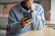 © bongkarn - Close up of a man looking at smartphone with hand holding chin while sitting at wooden table in cafe
