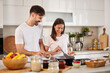 © Stockphotodirectors - In a stylish kitchen filled with natural light, a couple happily engages in cooking. They share smiles while using utensils and handling fresh ingredients, creating a warm and joyful environment.