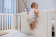 © leungchopan - Curious baby trying to climb playpen fence