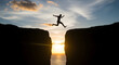 © Karmiyem - Man jumping over a chasm at sunset achieving goals success challenge leap of faith risk taking brave courageous determined motivation inspiration
