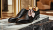 © Enti.std - Elegant pair of black leather dress shoes displayed on marble with shoe trees.