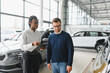 © Serhii - A consultant at a car dealership helps a customer choose a new car