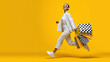© malik - Stylish shopper in the Spotlight: An elegant individual races with shopping bags against a vibrant yellow backdrop.