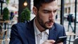 © maxximmm - Man suit looking at his phone. Man in suit and a smartphone in a cafe. Professional texting business in the city. A man dressed in a suit is gazing at his phone lifestyle.