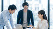 © Blue Studio - 3人の日本人ビジネスパーソンがノートパソコンを使って行うオフィスでの打ち合わせ