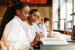 © Drobot Dean - Two female students are sitting at a table and holding pens while looking at a book