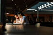 © Drobot Dean - Two female students talking and looking at a book while sitting at a table