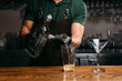 © Iryna - Bartender pouring alcoholic drink into glass using jigger and metal pour spout