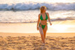 © Parilov - Young caucasian female enjoying beach walk at sunset in green bikini