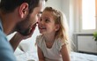 © wu - A little girl is sitting on a bed in a bedroom while her father booping her nose. High quality