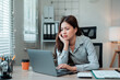 © Crystal - Young Asian businesswoman feeling stressed and exhausted while working on a laptop at her office desk, facing tight deadlines and pressure