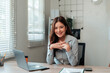 © Crystal - Young Asian businesswoman smiling and posing at her desk in a modern office, successful entrepreneur concept
