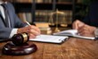 © Haikalceriativemark - Lawyers signing documents at a table, gavel in foreground