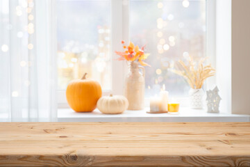 Wall Mural - Halloween wooden table space in front of blurred window with holiday decorations as background for product montage