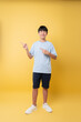 © Q88 - Smiling young person points off camera dressed casually against vibrant yellow backdrop Friendly pose