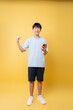 © Q88 - Enthusiastic young man celebrates success holding phone against a bright yellow backdrop