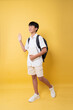 © Q88 - Enthusiastic student cheerfully waves hello ready for school with backpack and book in hand