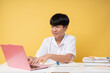 © Q88 - Student using laptop for online learning bright yellow background focused and studious