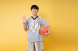 © Q88 - Teen basketball player in a grey uniform and shorts giving an ok sign holding his ball