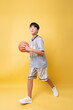 © Q88 - Young basketball player with ball on yellow backdrop ready for a game sport and active lifestyle
