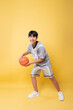 © Q88 - Smiling athlete ready to play ball Young athlete holding a basketball on a yellow background