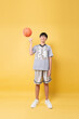 © Q88 - Youthful basketball player displays ball handling skills on a sunny yellow backdrop Determination