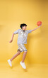 © Q88 - Young basketball player leaps against a yellow backdrop with a ball showcasing athletic prowess