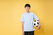 © Q88 - Teen boy with soccer ball in studio: youthful energy athleticism and fun on yellow background
