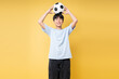 © Q88 - Teenager smiles while balancing a soccer ball on his head against a bright yellow background