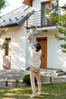 © Maria Vitkovska - Father lifting daughter in the air in front of house