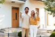 © Maria Vitkovska - Happy couple celebrating buying new house showing keys in front of home