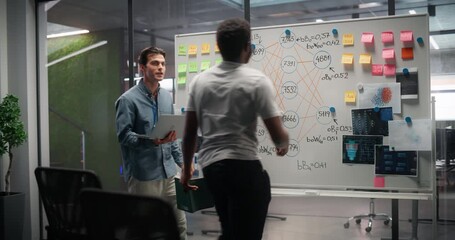 Two Colleagues are Brainstorming Technology Ideas on a Whiteboard, Discussing a Quantum Computing System. Young Diverse Engineers Working on AI in a Research and Development Office 
