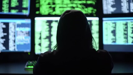 Hacker working on multiple computer screens displaying code.