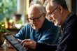 © Vitalii Shkurko - Two senior men are seated at a table while exploring digital content on a tablet. The warm atmosphere includes indoor plants and soft natural lighting, enhancing their focused interaction