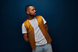 © Bliss - Confident young Black man in trendy outfit poses against a dark backdrop