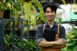 © saltdium - Small business owner in apron smiling while managing his plant shop digitally