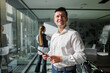 © muse studio - Professional man in white shirt holding tablet smiles while colleague works in modern office
