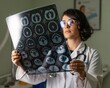© Sarkar - Female doctor examining brain MRI scan in a medical office healthcare