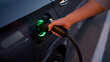 © Magic - Charging an Electric Car: The electric vehicle is being charged, and a person is attaching a charging cable to the car
