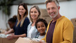 © Nataliya - A diverse family volunteering at a local food bank, sharing authentic moments of giving, using both traditional methods and digital coordination apps, diverse families, authentic m