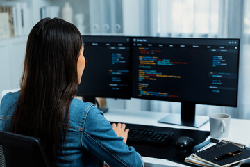 Young Asian in IT developer creating with typing online information on pc with coding program data of website application, wearing jeans shirt. surrounded by safety analysis two screens. Stratagem.