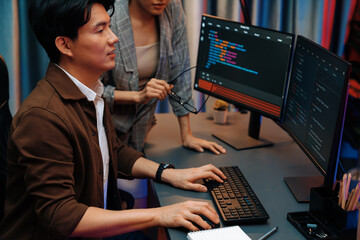 IT developers discussing with point to intelligent website development coder system running data online two screens information technology at neon light room at modern office. Infobahn.
