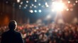 © Huzaifa - Speaker addressing a large audience in a conference hall with spotlights and bokeh lights