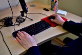 Manos de hombre joven sobre teclado de computador.
