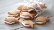 © Tarakan - Fish-shaped cookies, filled with white cream, in a clear bag, on a light wood surface