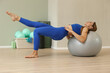 © zhagunov_a - Fit woman exercising on stability ball in blue activewear