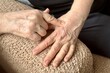 © vipvn - An unfamiliar elderly woman makes herself a hand massage with a massager, presses on specific places on the bones of the arm and skin