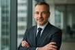 © Bijac - Experienced corporate leader in sleek modern office confident mature executive portrait with arms crossed under natural window light