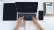 © tippapatt - Overhead shot of business woman hand typing on laptop computer with digital tablet, smartphone and paper notebook, business document on white office desktop, business background
