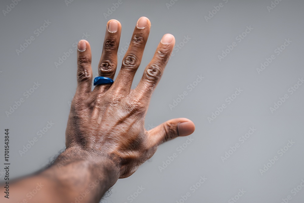 Raised hand with blue ring on finger against neutral background ...